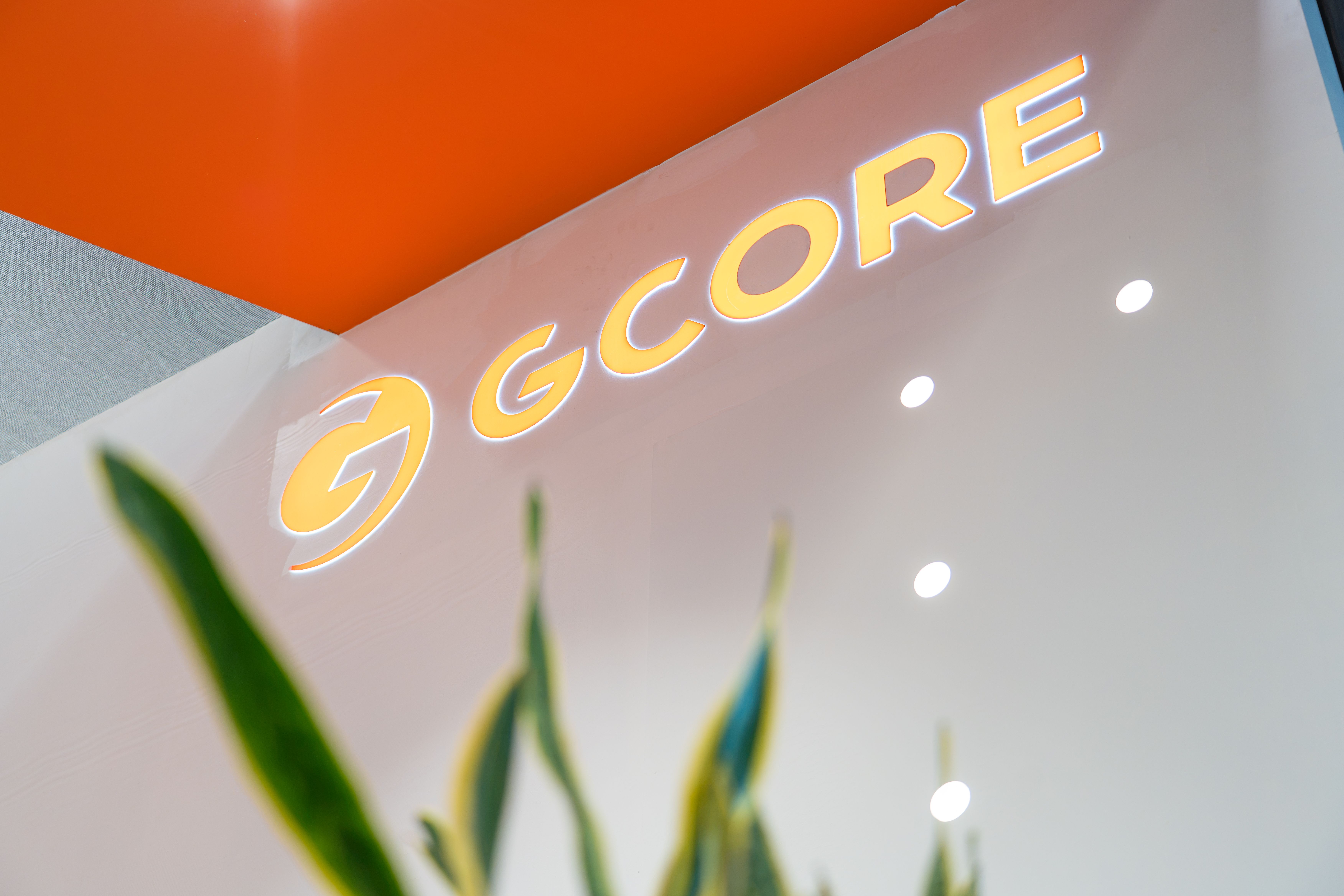 Glowing yellow GCORE logo displayed prominently on an orange and white wall.