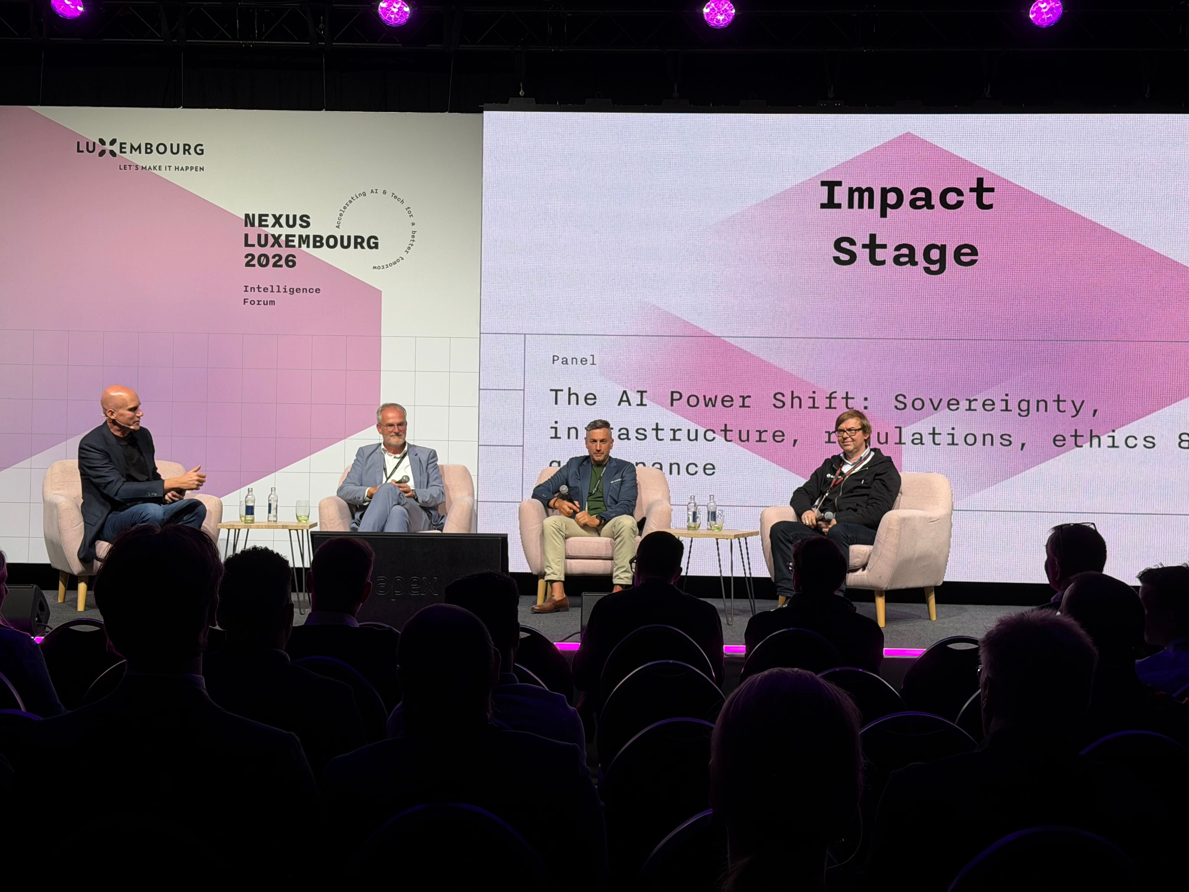 Four men on stage at a conference panel discussing 'The AI Power Shift'.